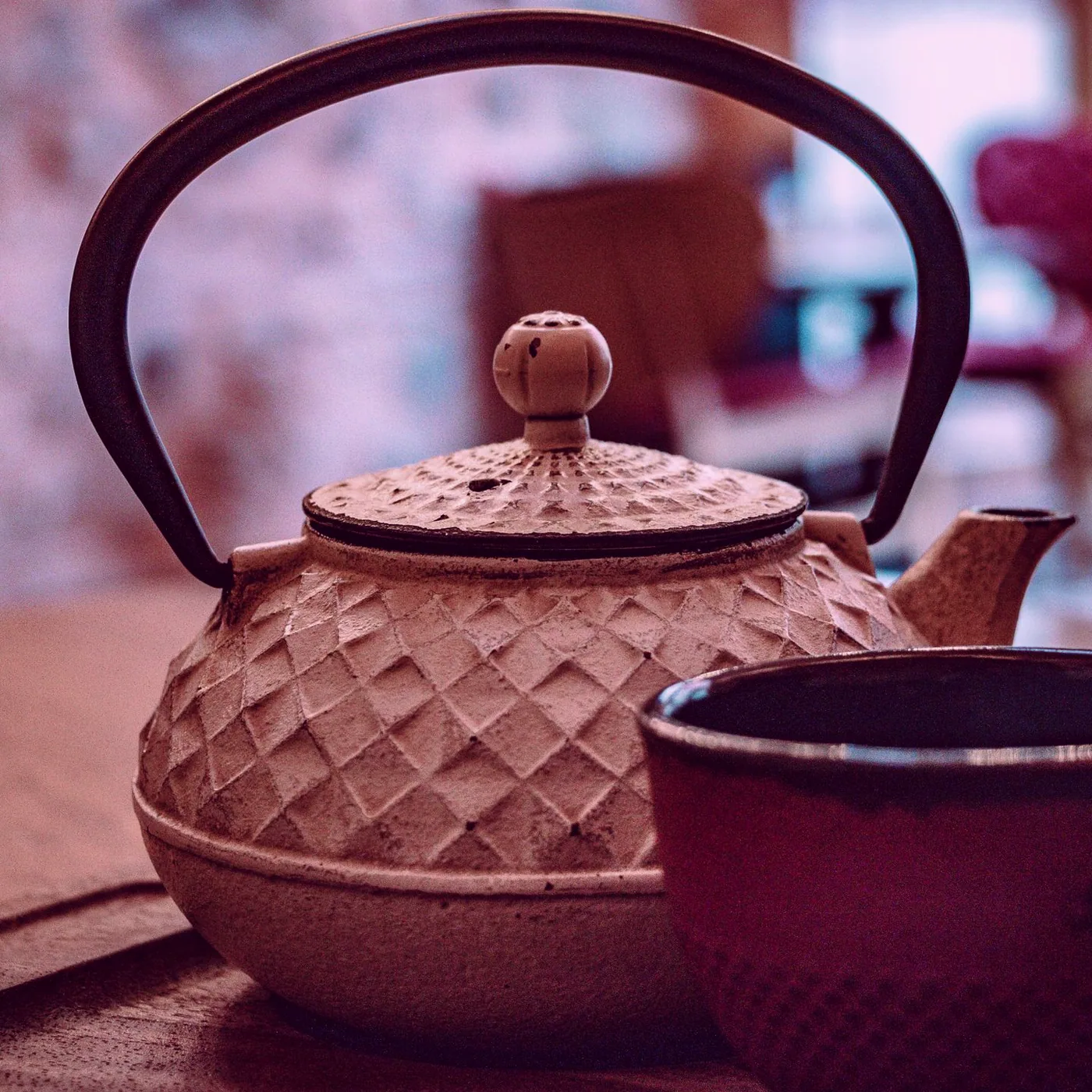 A white ceramic mug of tea steaming on the counter beside the old ledger shelf.